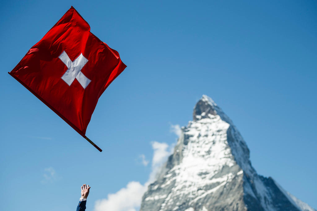 A Swiss flag is thrown in the air with the Matterhorn in the background