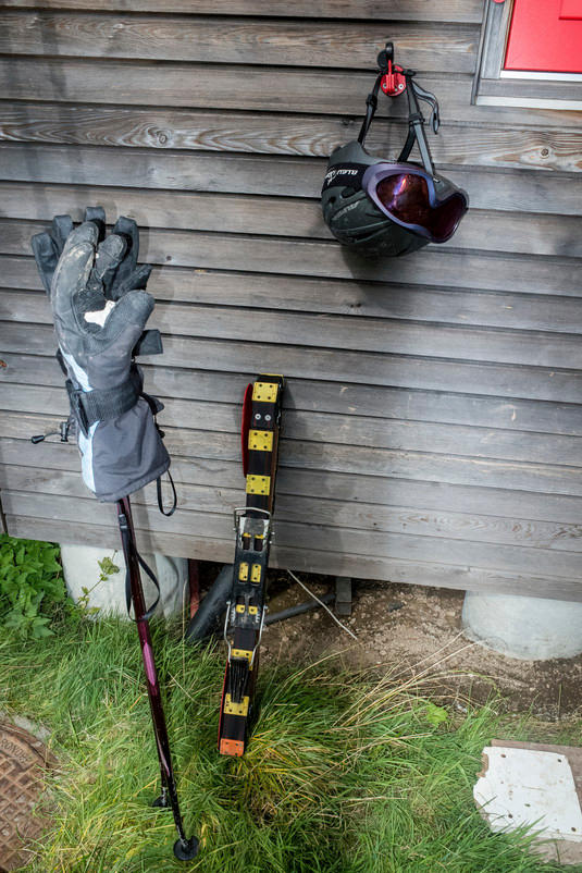 木の壁に立てかけられた草スキーの板、手袋、ヘルメット
