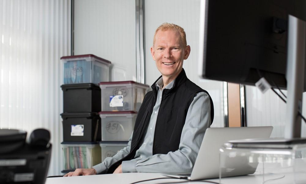 Johann Gevers smiles as he sits at his desk