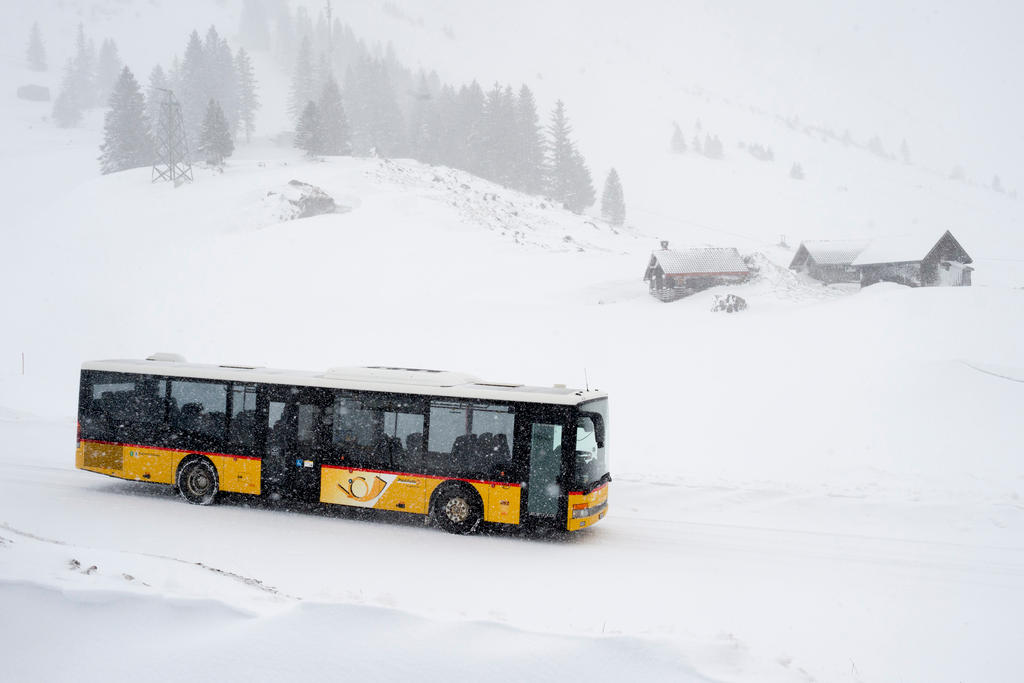 A PostBus drives through the snow