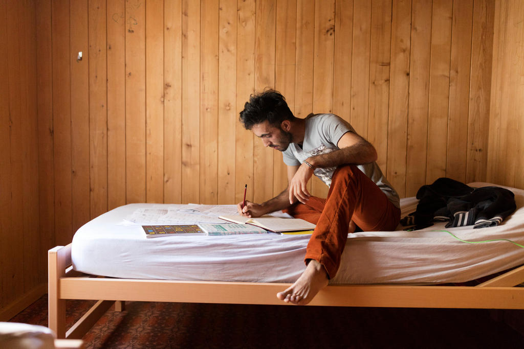 Homem na cama escrevendo em um caderno