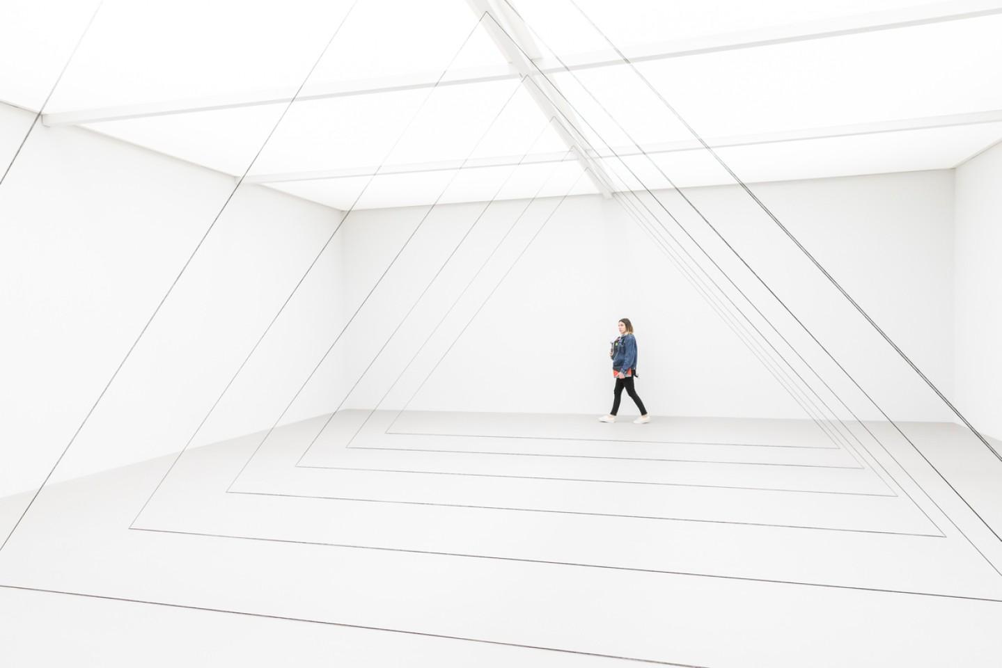 una donna cammina all interno di un grande spazio di colore bianco