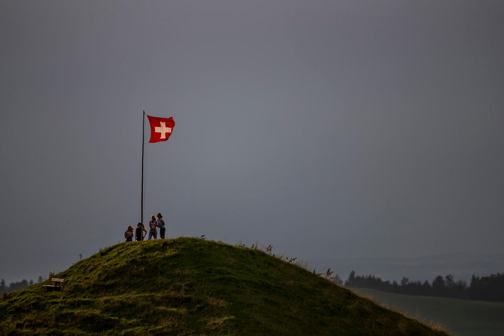 Schweizer Fahne und vier Wanderer auf einem Hügel