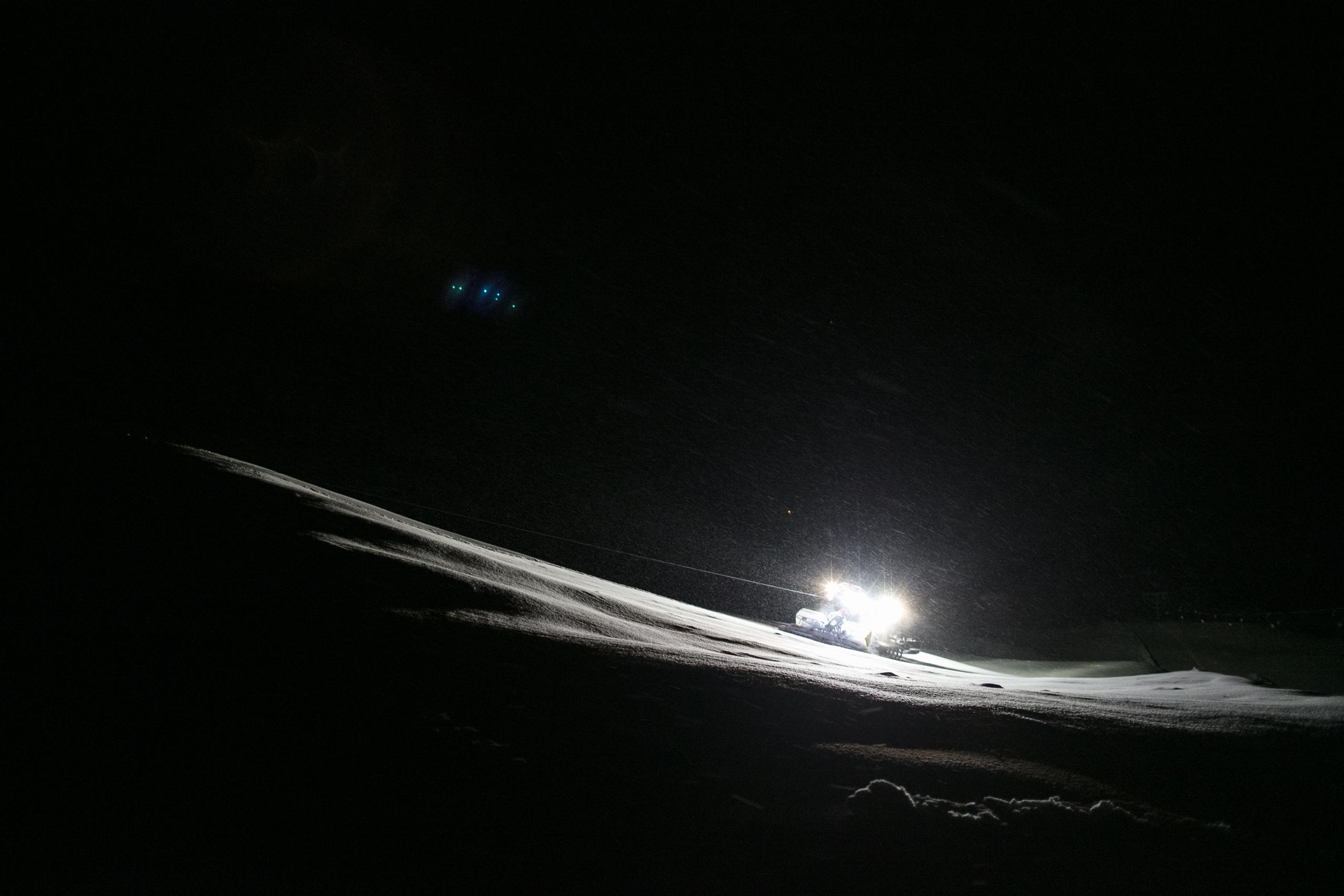 Trator de pista iluminado na noite nevada