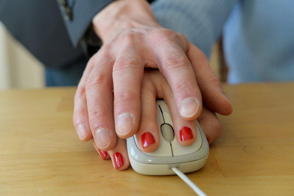 パソコンのマウスの上に重なる男性と女性の手