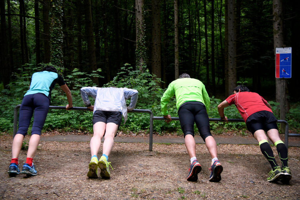 Vier Personen an einem Gerät auf dem Fitness-Parcours im Wald