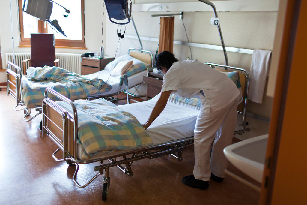 Una auxiliar de enfermeria hace una cama