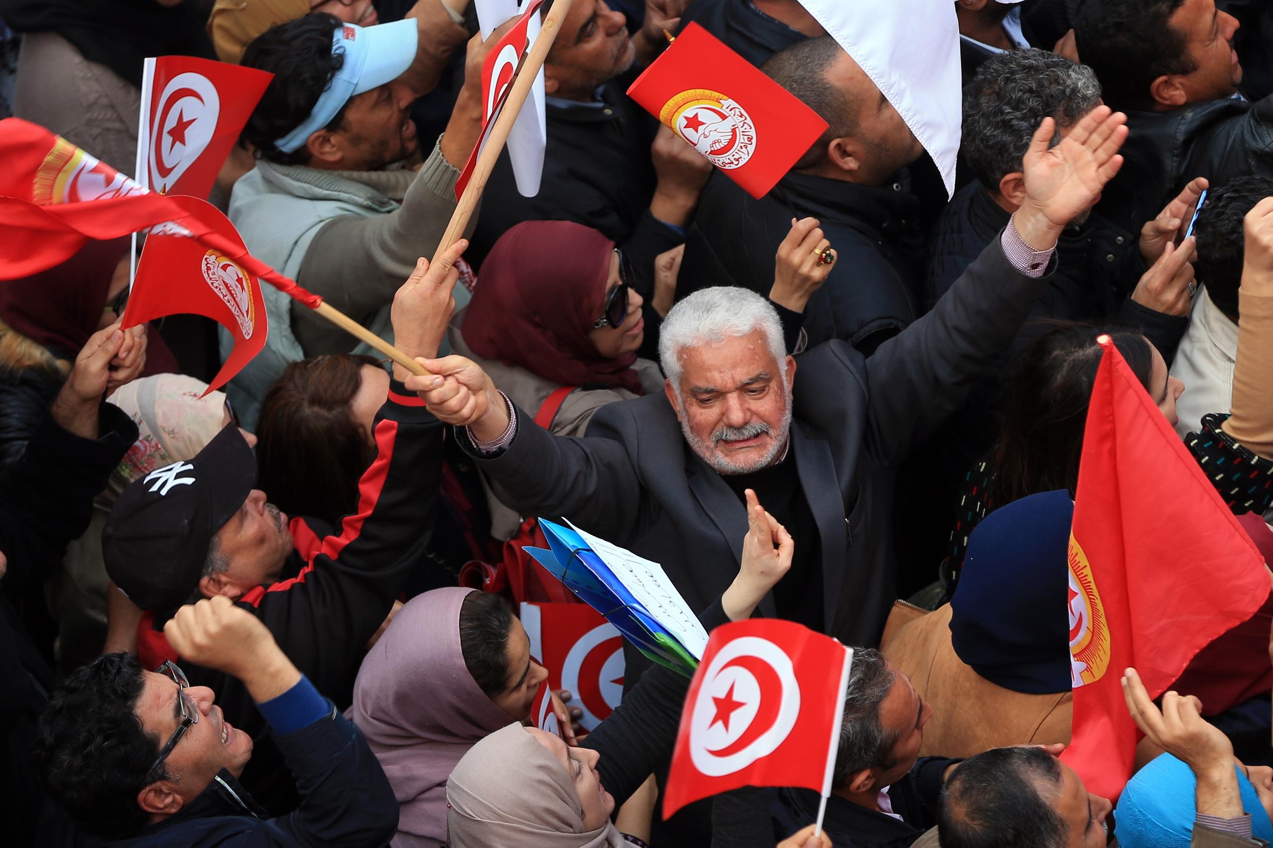 manifestazione in cui vengono sventolate bandiere tunisine.