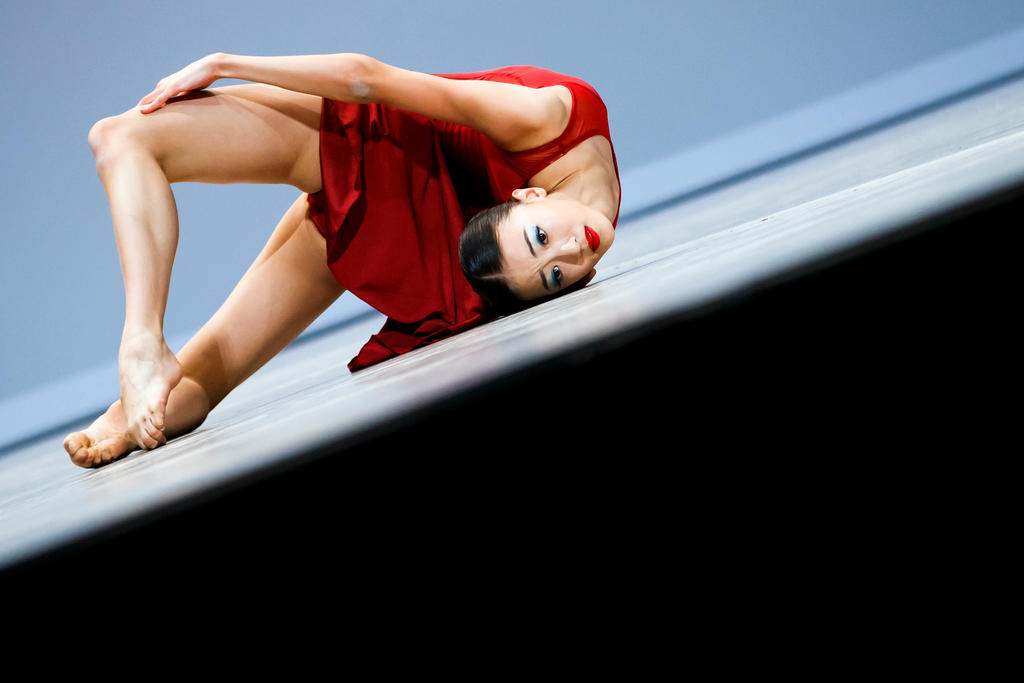 Dancer in red dress poses on floor
