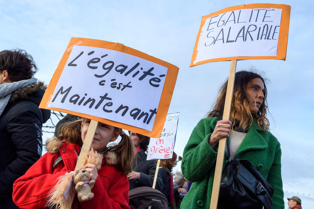 Una mujer y una niña con pancartas durante manifestación en pro de igualdad salarial entre hombres y mujeres.