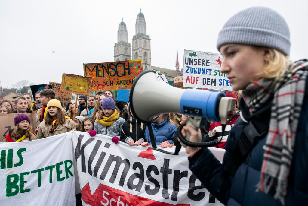 Junge Frau mit Megaphon an der Spitze von Demonstrierenden gegen Klimapolitik.