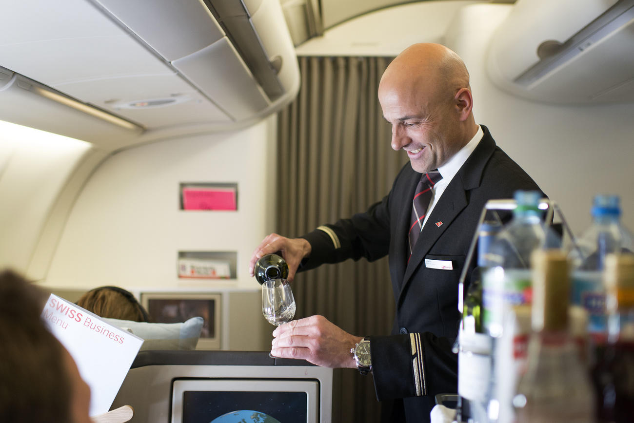 A flight attendant attends to Swiss Business Class passengers