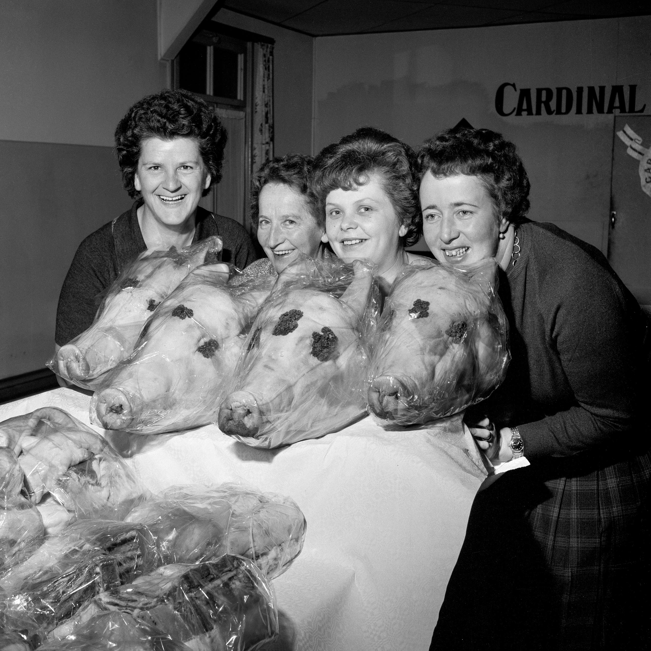 Quatre femmes posant avec des têtes de porc