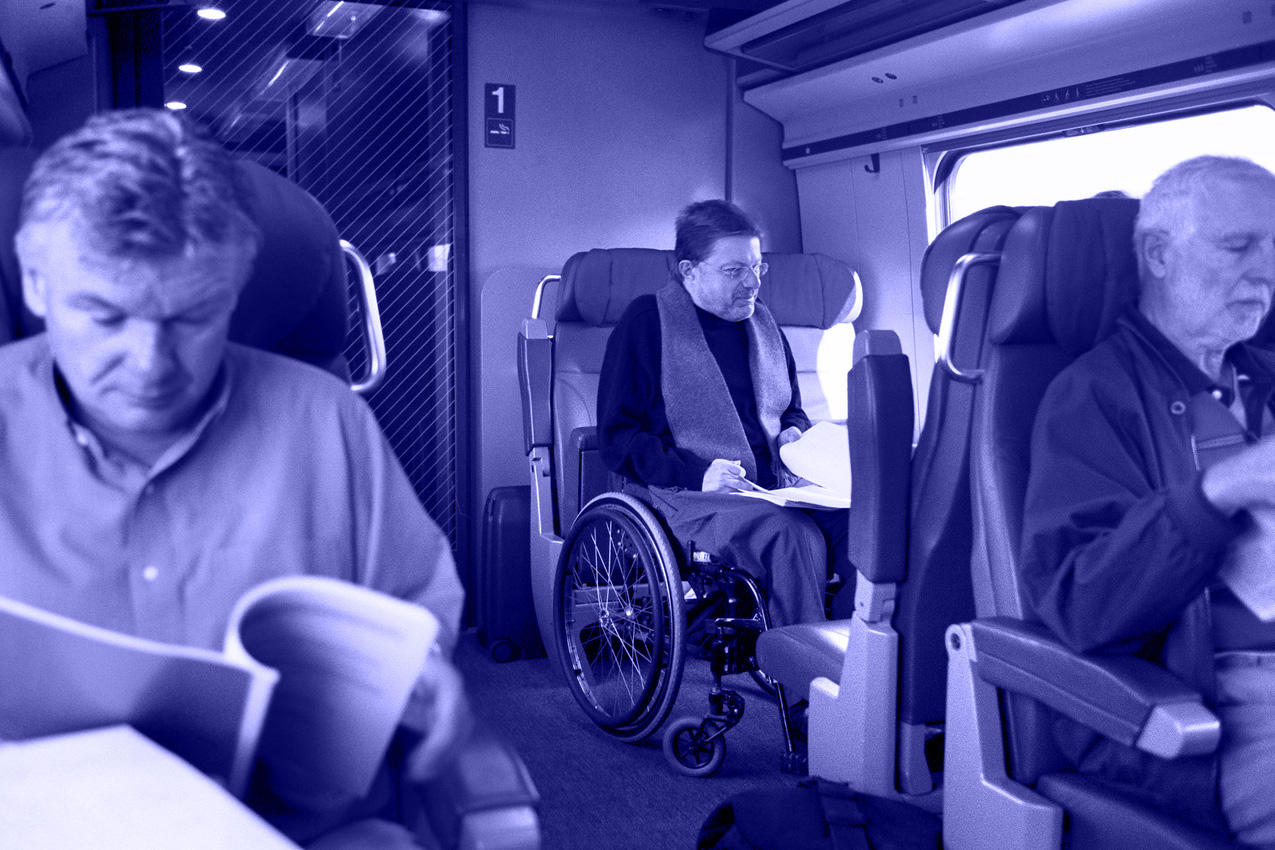 Un hombre se sienta en una silla de ruedas en un compartimento de tren.