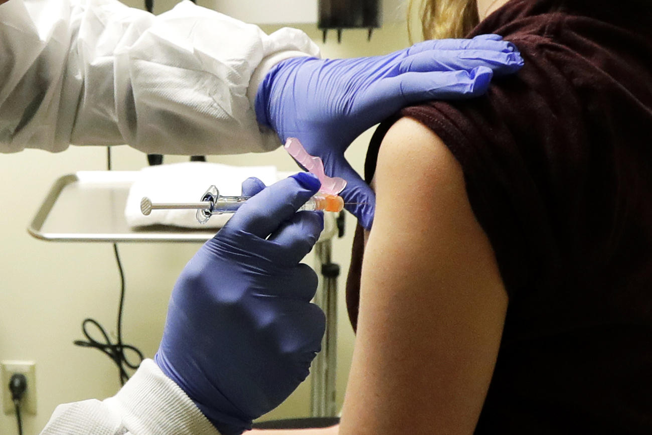 Persona pone a una inyección en el brazo de una paciente
