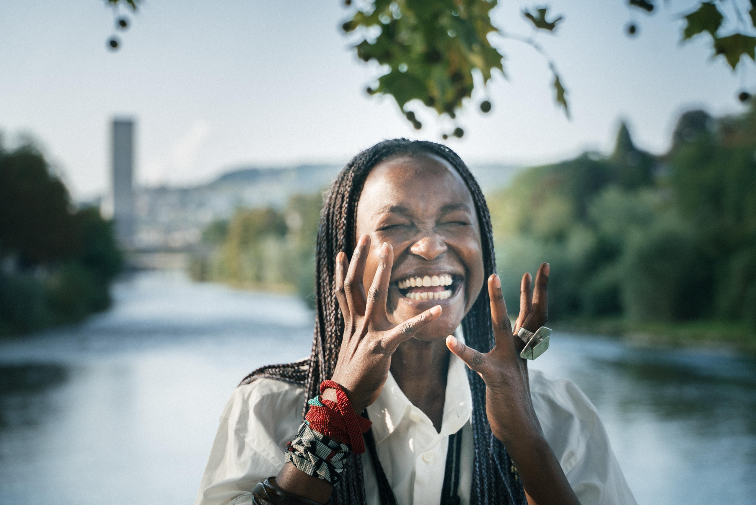 Femme noire souriante posant devant une rivière.