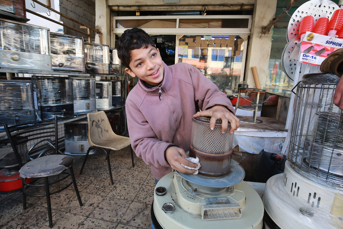 Jordanian teenager, Omar, 14, fixes a kerosene heater in a workshop where he works in Amman.