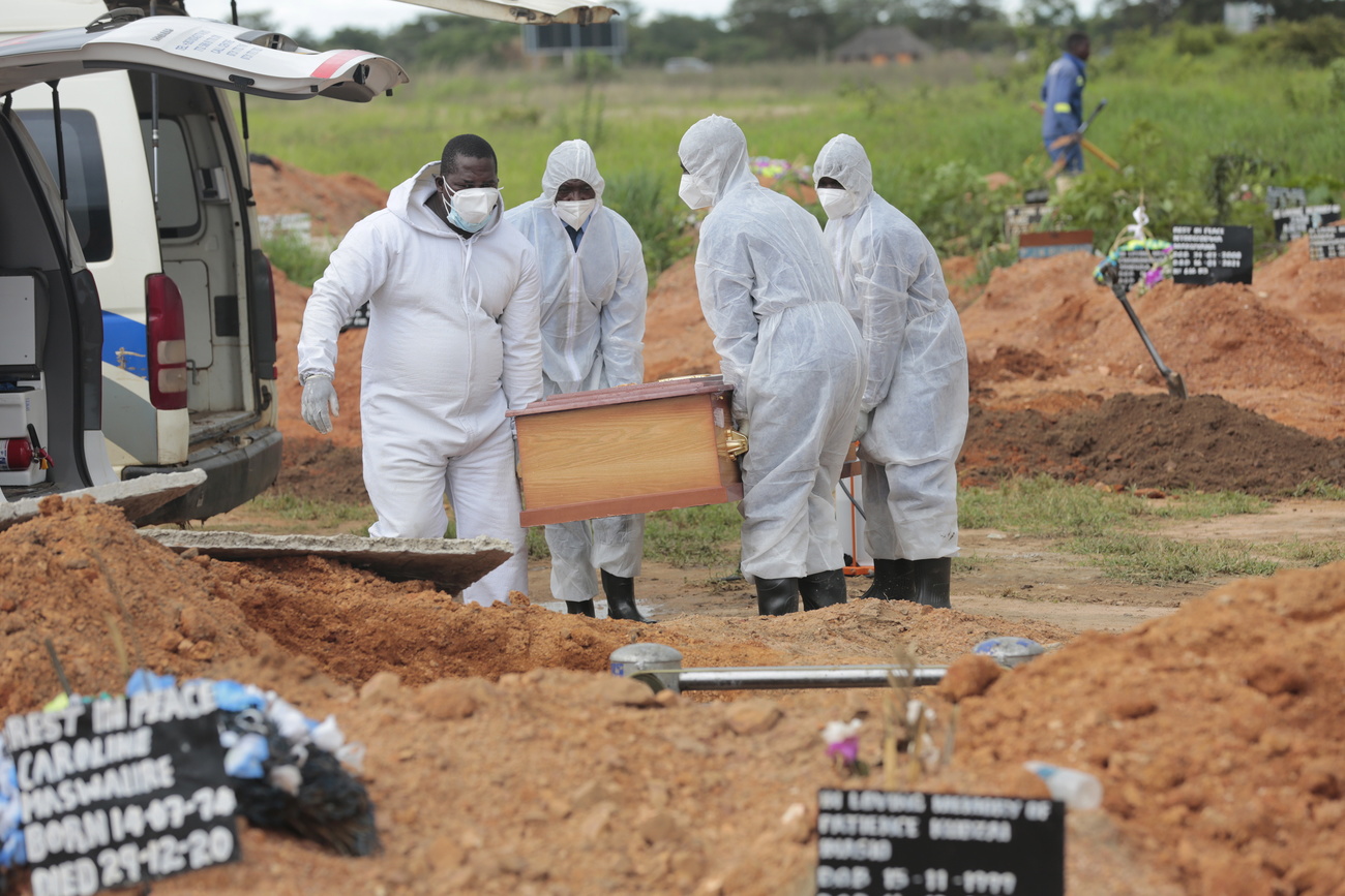Funeral workers in Zimbabwe lower the coffin of a Covid victim into the ground