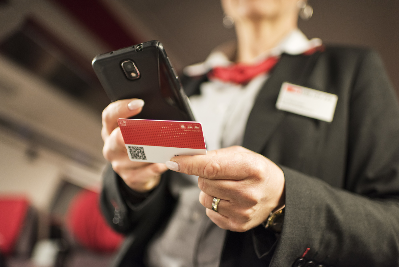 A conductor checks a Swisspass card on a train