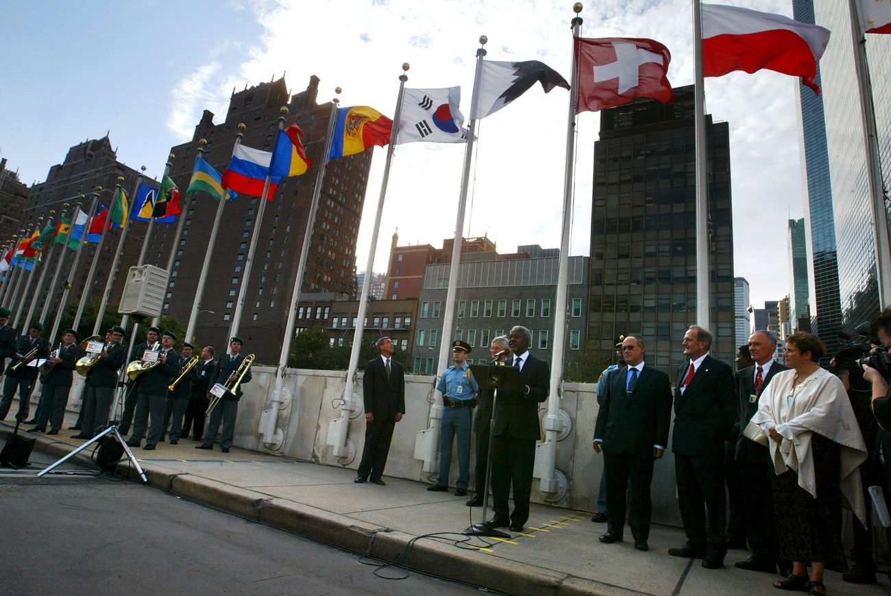 Kofi Annan ante el micrófono frente a la sede de la ONU, rodeado de personas.