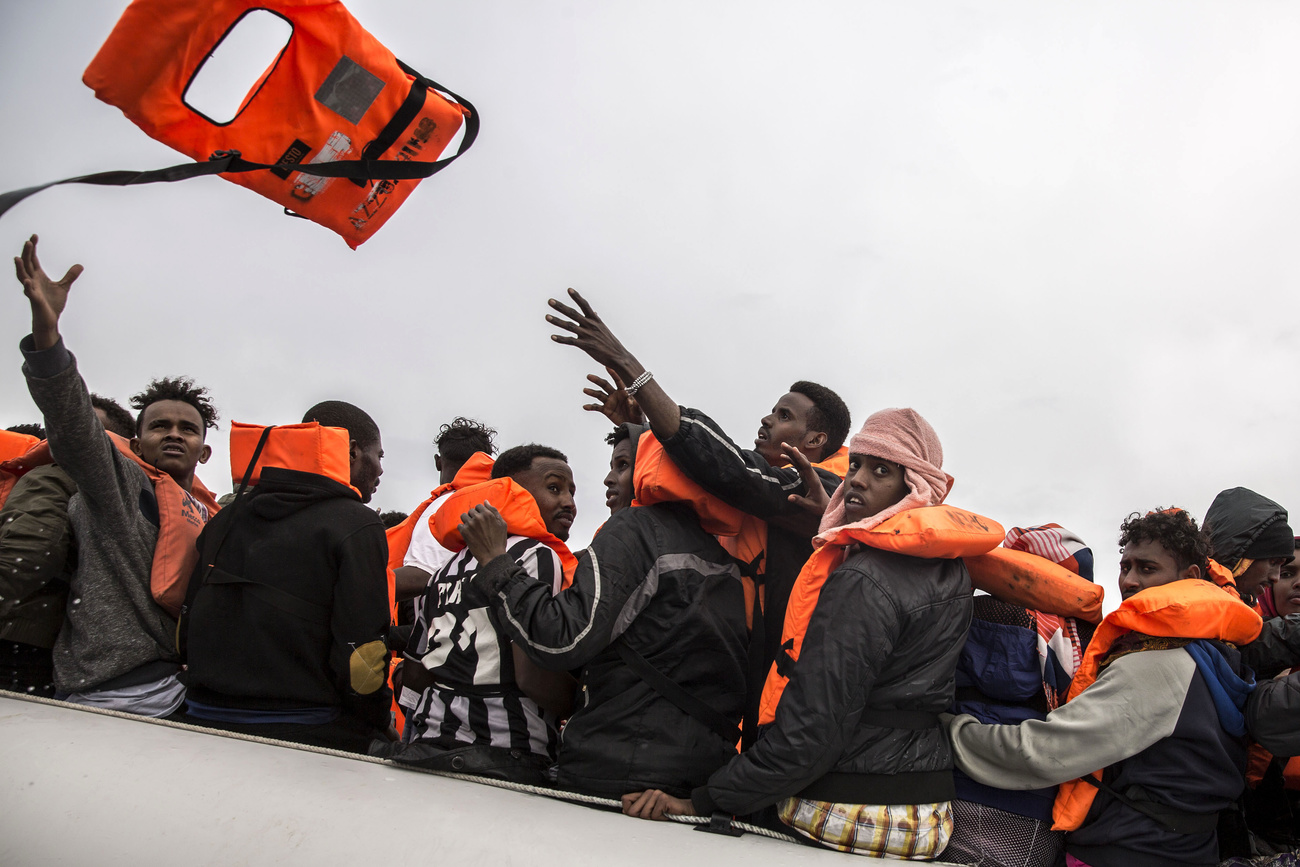 Refugees in a dinghy wearing orange life jackets
