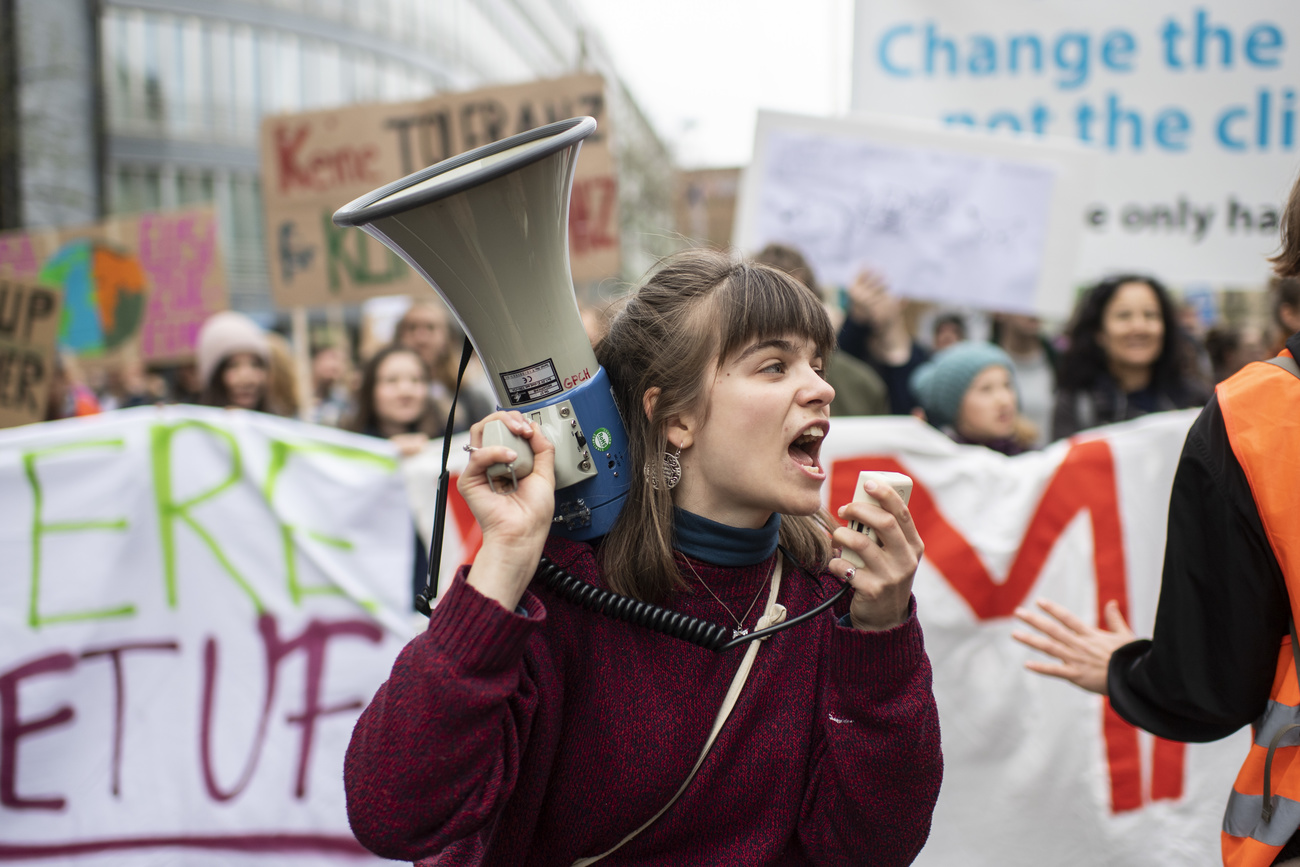 Jovem mulher com megafone em marcha de protesto contra o clima