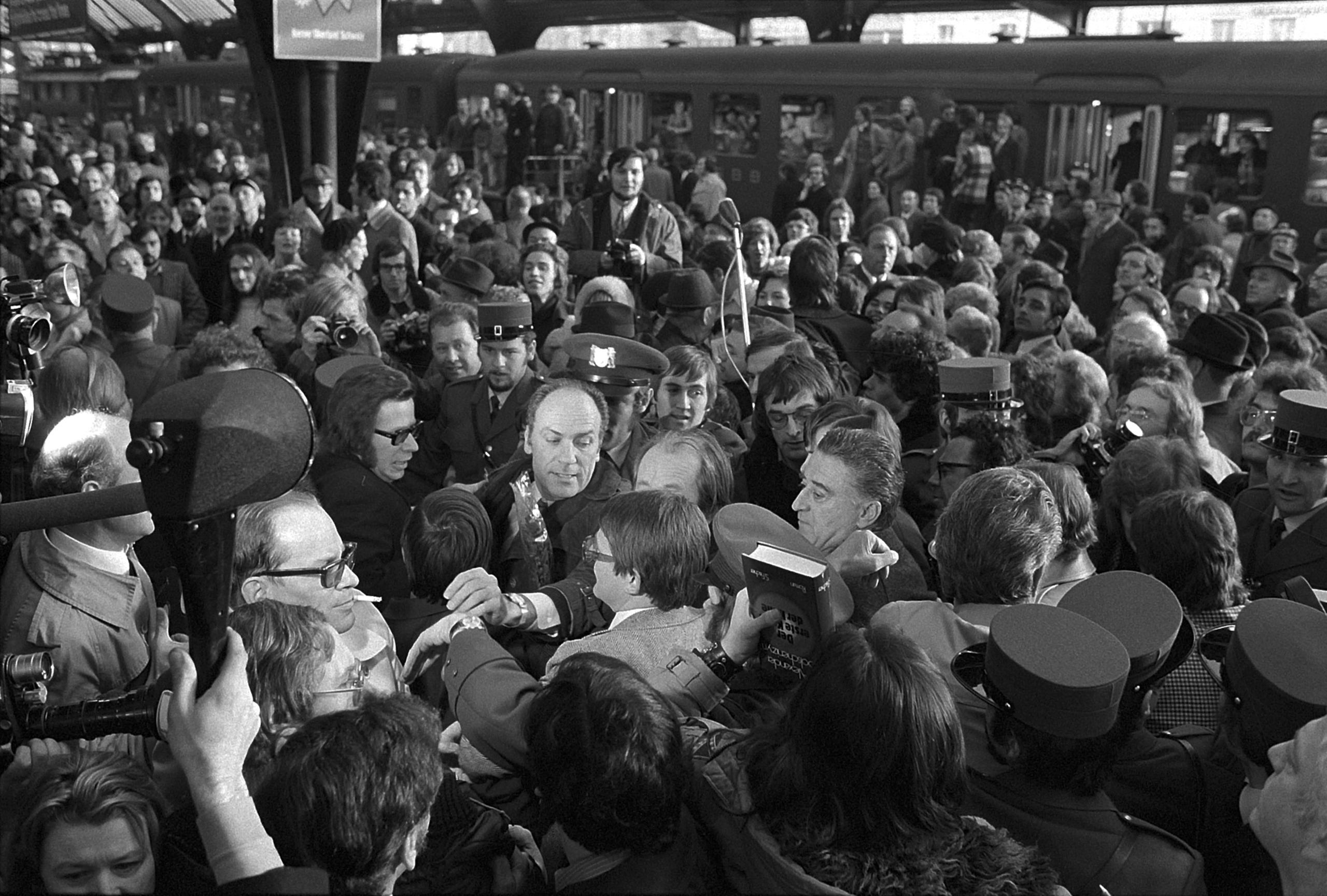Foule entourant un homme dans une gare