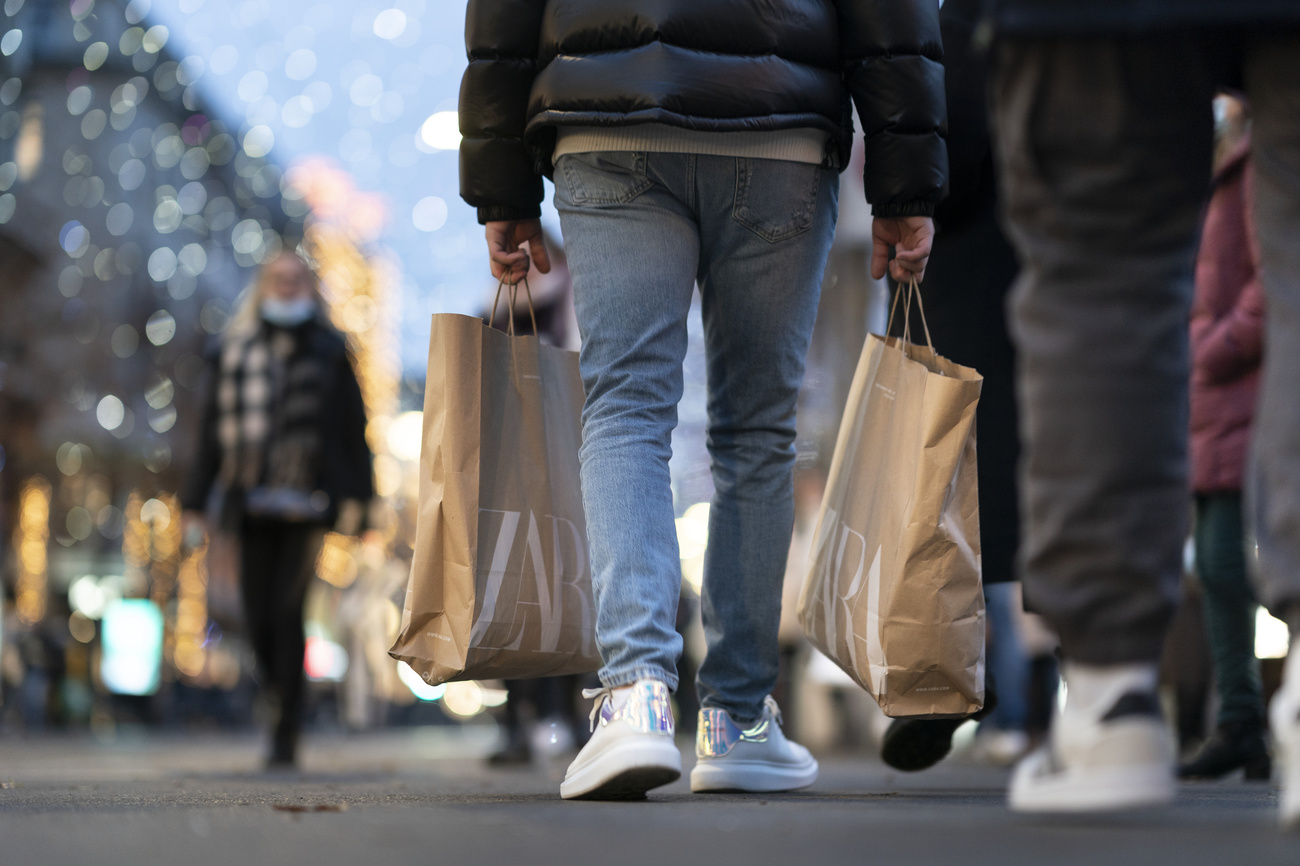 Imagen parcial de una persona caminando por la calle con bolsas de compras