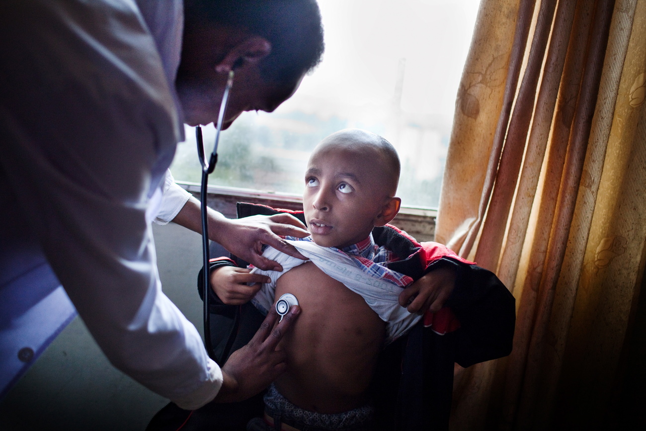 Un niño mira al médico que lo ausculta.
