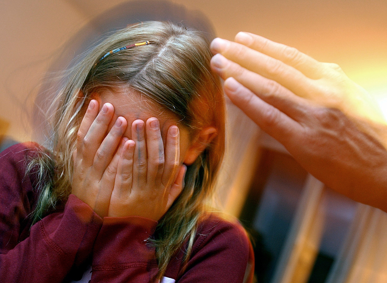 Una niña se cubre la cara de un golpe en imagen escenificada.