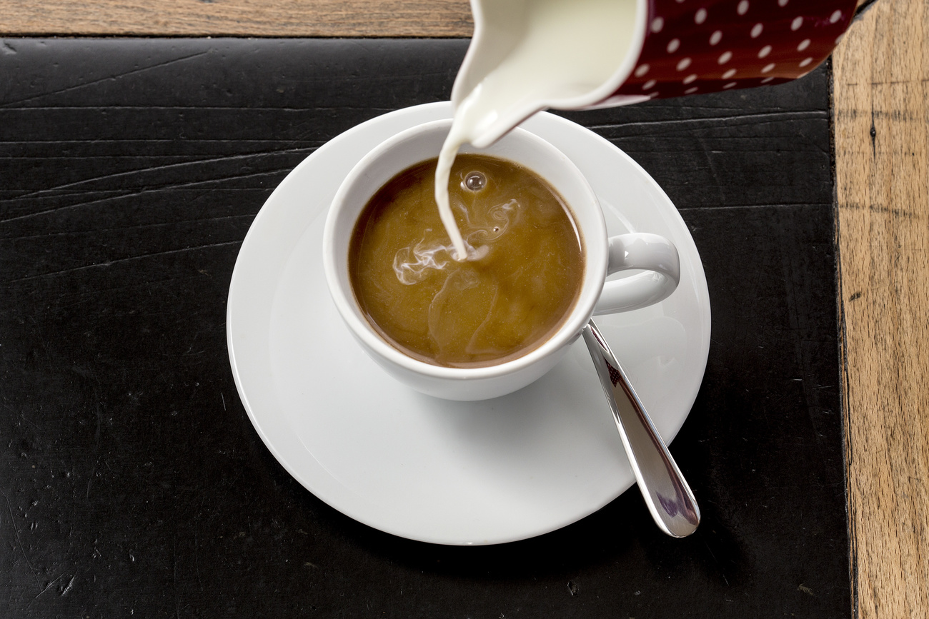 O leite é derramado em uma xícara de café
