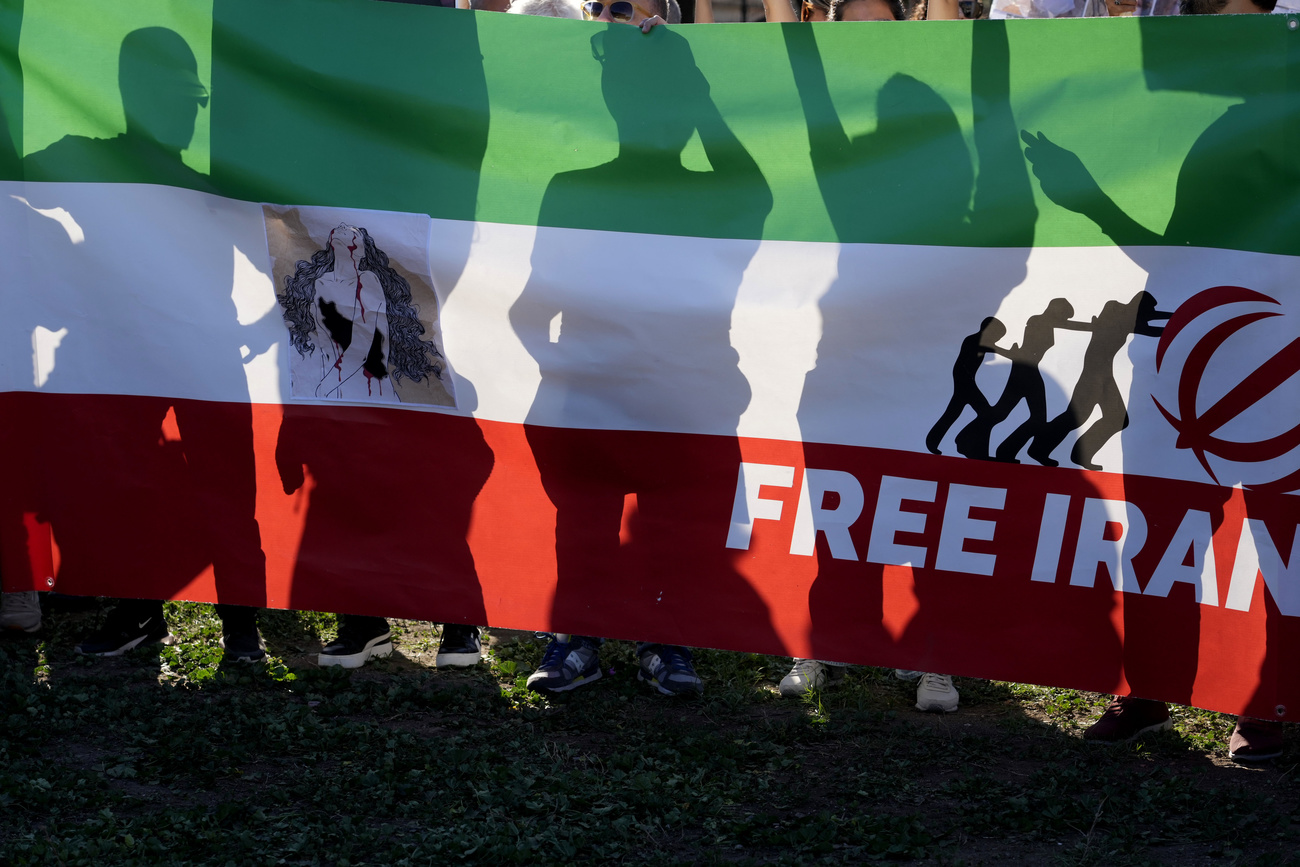 Protestantes atrás de uma bandeira iraniana