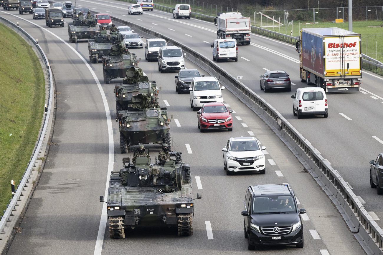 Armoured cars travel down a highway with normal traffic in Switzerland.