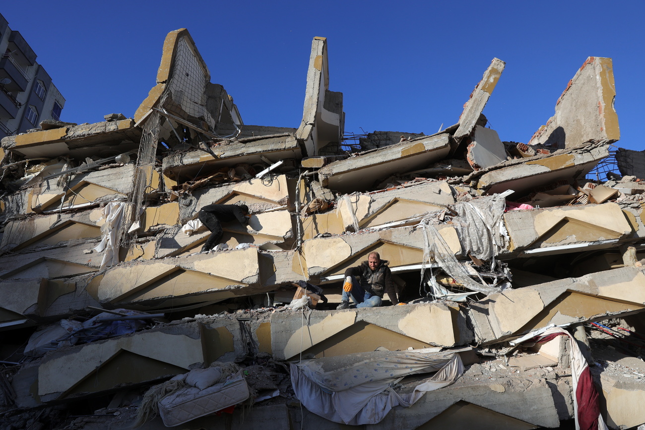 رجل يجلس فوق أنقاض بناية بطوابق انهارت في مدينة قهرمان ماراش جنوب شرق تركيا