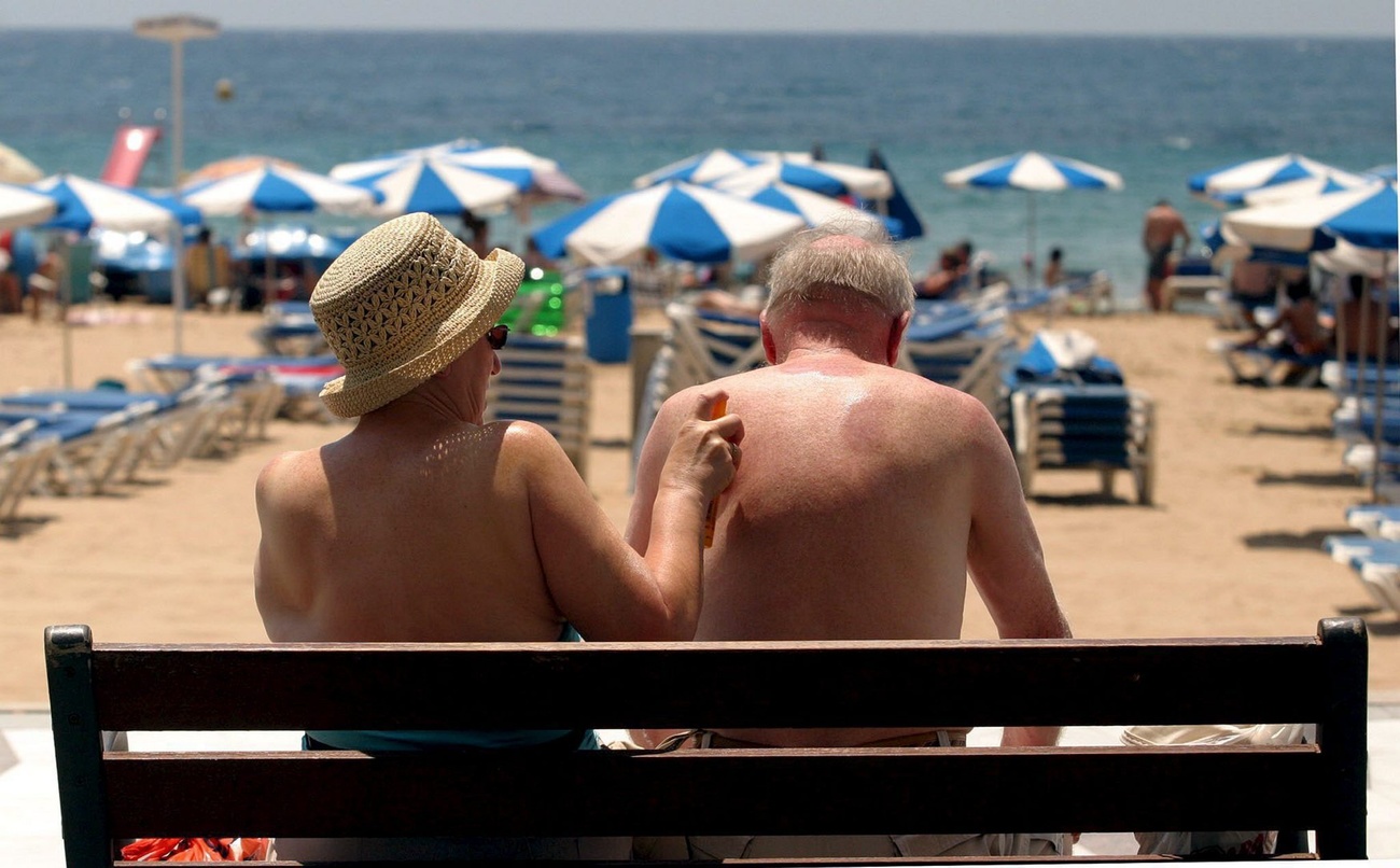 صورة من الخلف لرجل وامرأة جالسيْن فوق مقعد على شاطئ