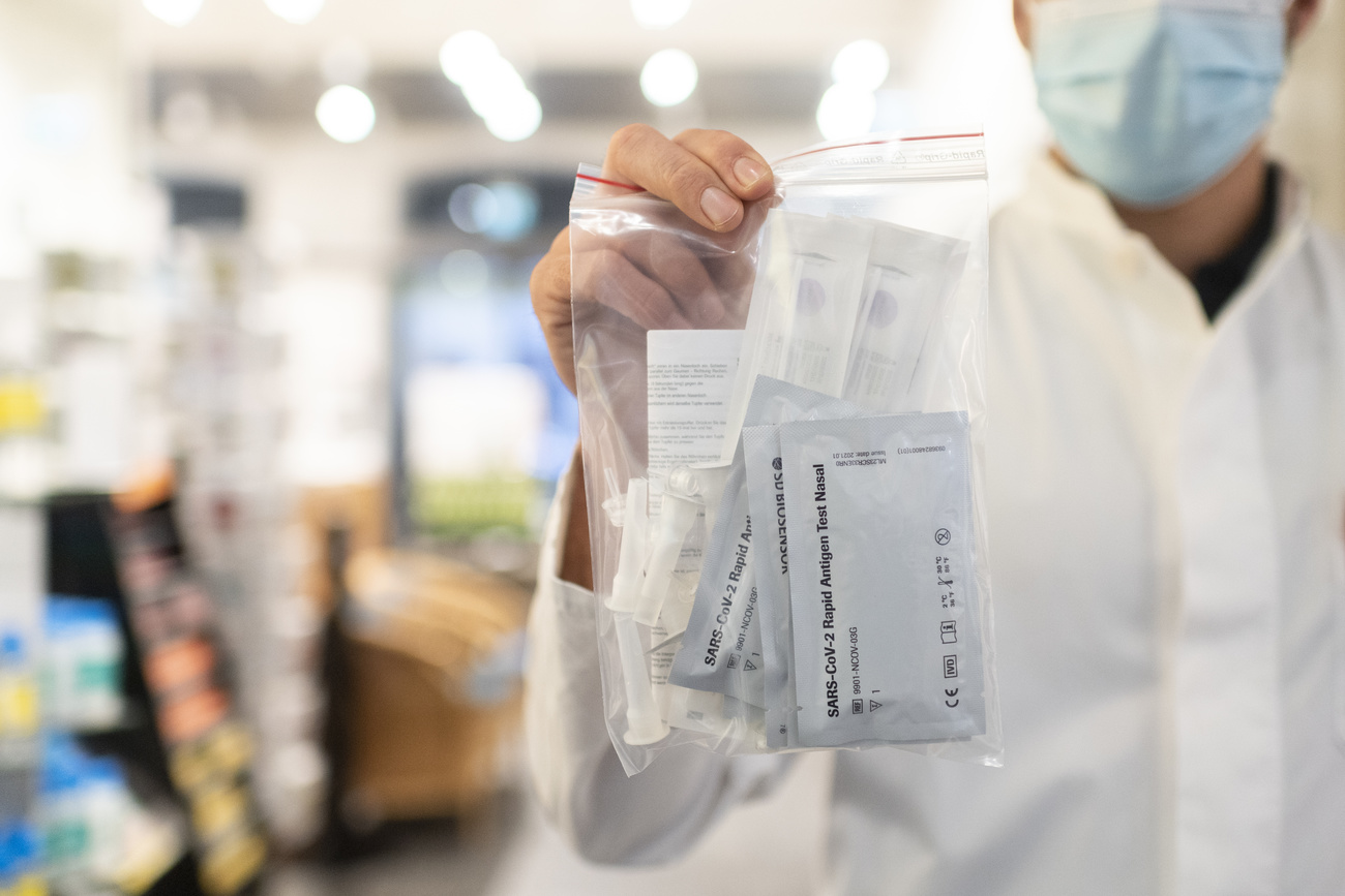 Masked man holds up bag of Covid testing kits