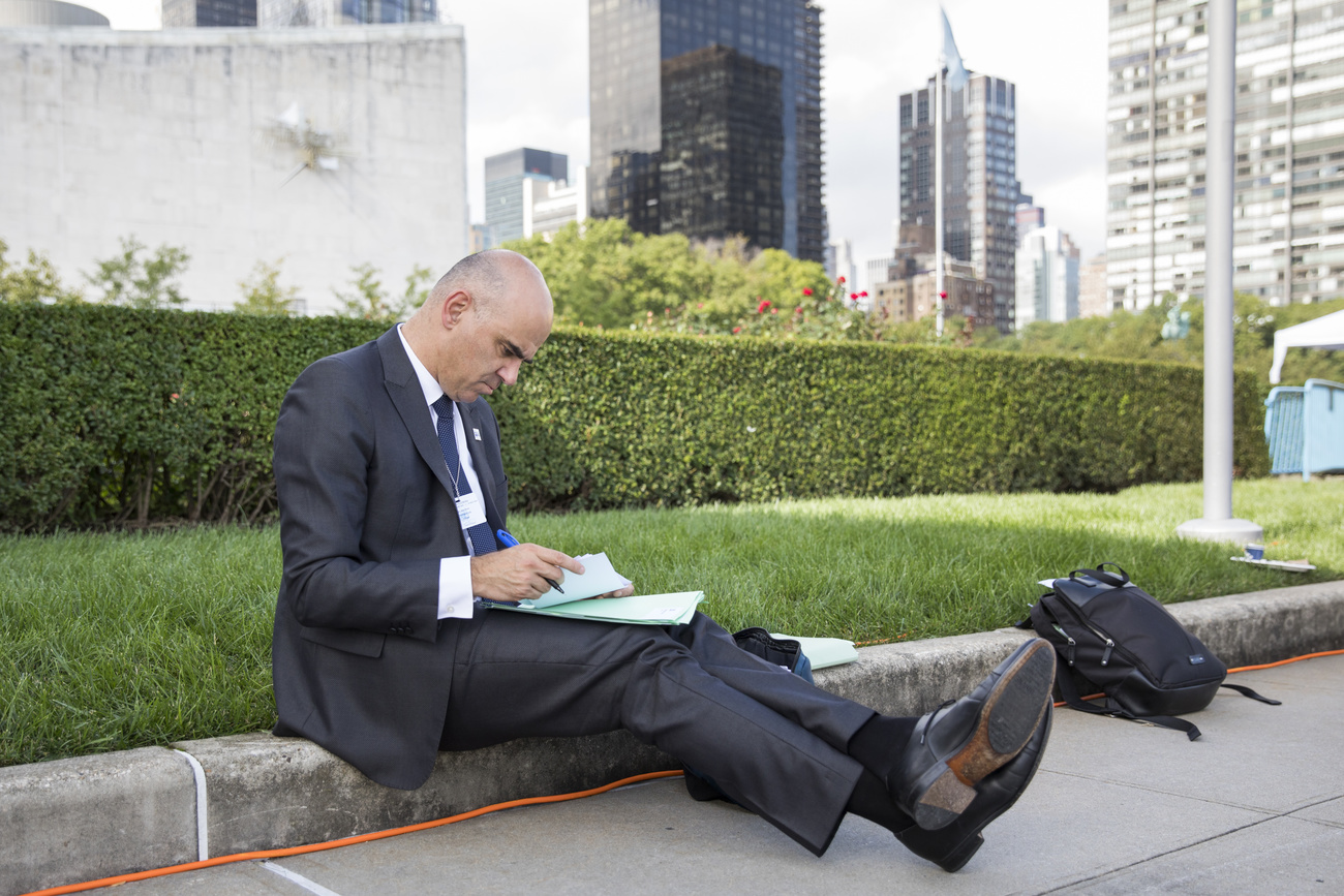 Man in black suit sits on the pavement in New York and takes notes