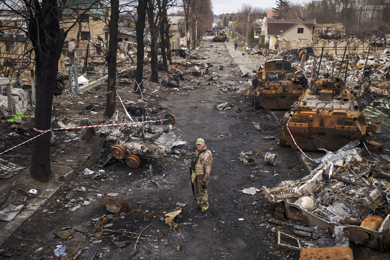 A Ukrainian serviceman stands amid destroyed Russian tanks in Bucha, Ukraine