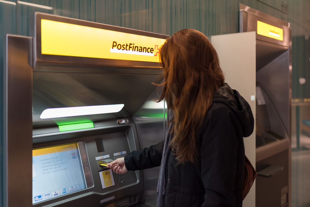 Una mujer saca dinero del cajero automático de PostFinance