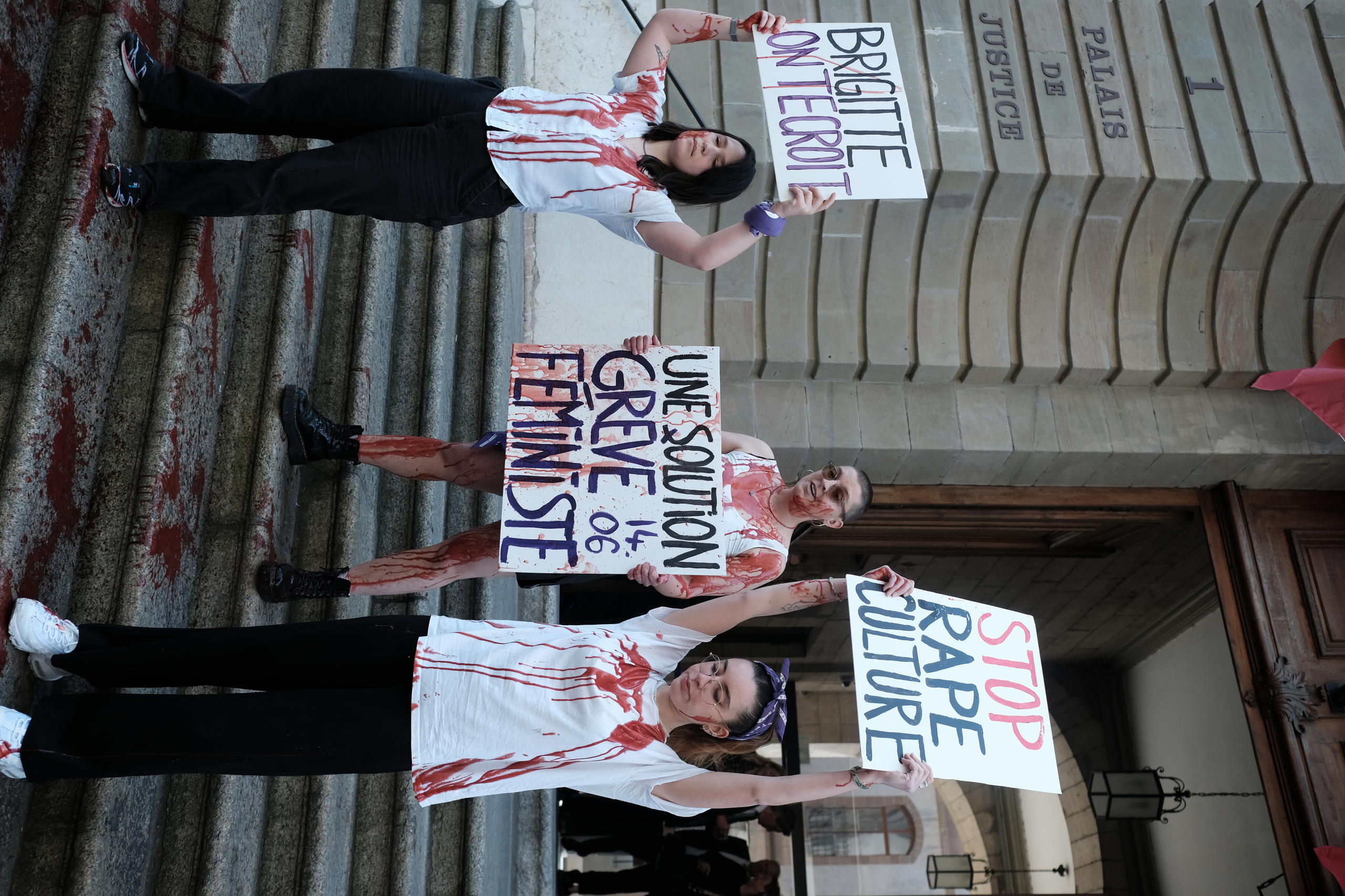 Photo of some women holding signs against sexual violence covered in fake blood