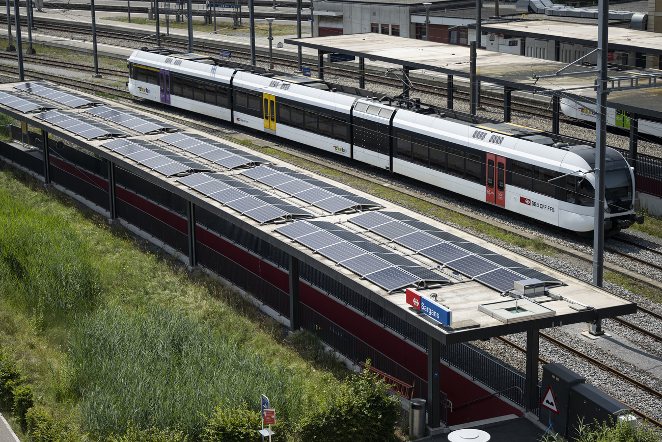 Un tren suizo pasa junto a una instalación de paneles solares