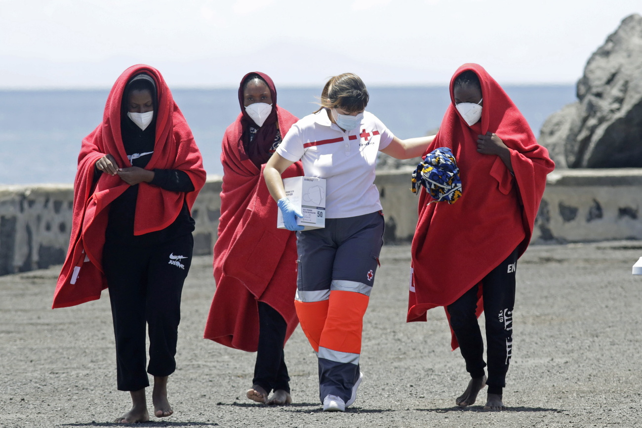 Foto di una donna che aiuta tre rifugiati