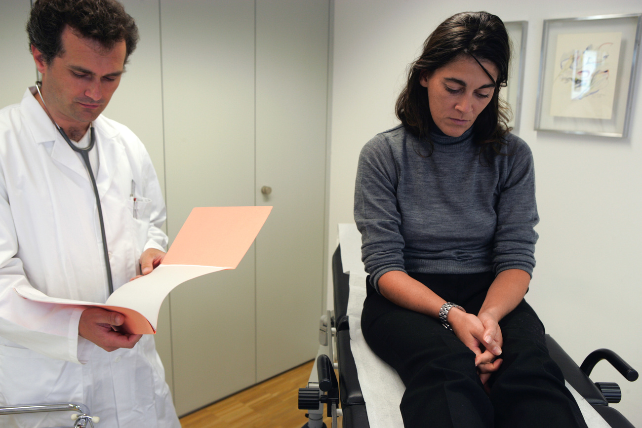 Photo of a doctor and a woman sitting on a doctor s bed