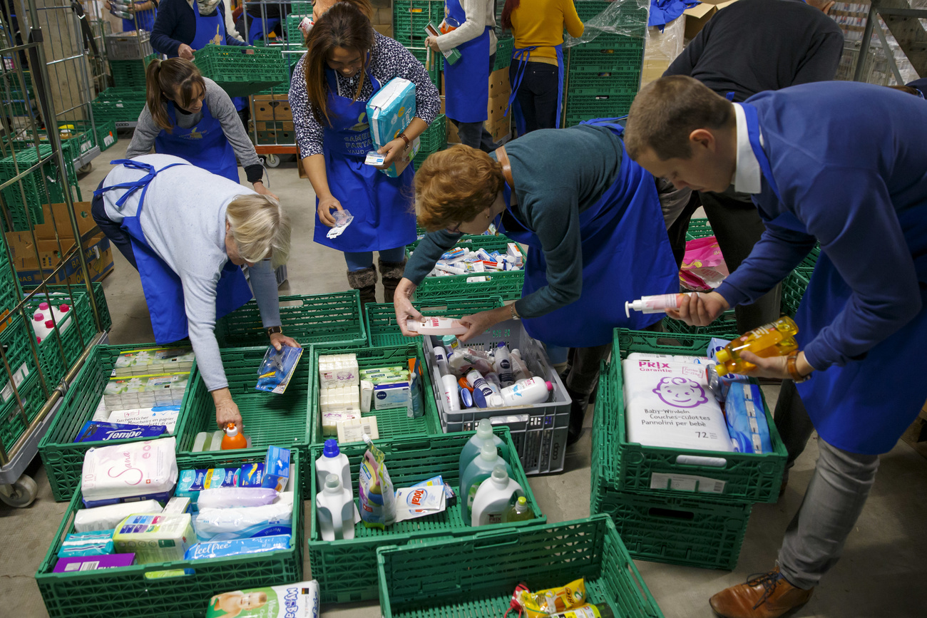 Personale della Caritas seleziona cassette di cibo.