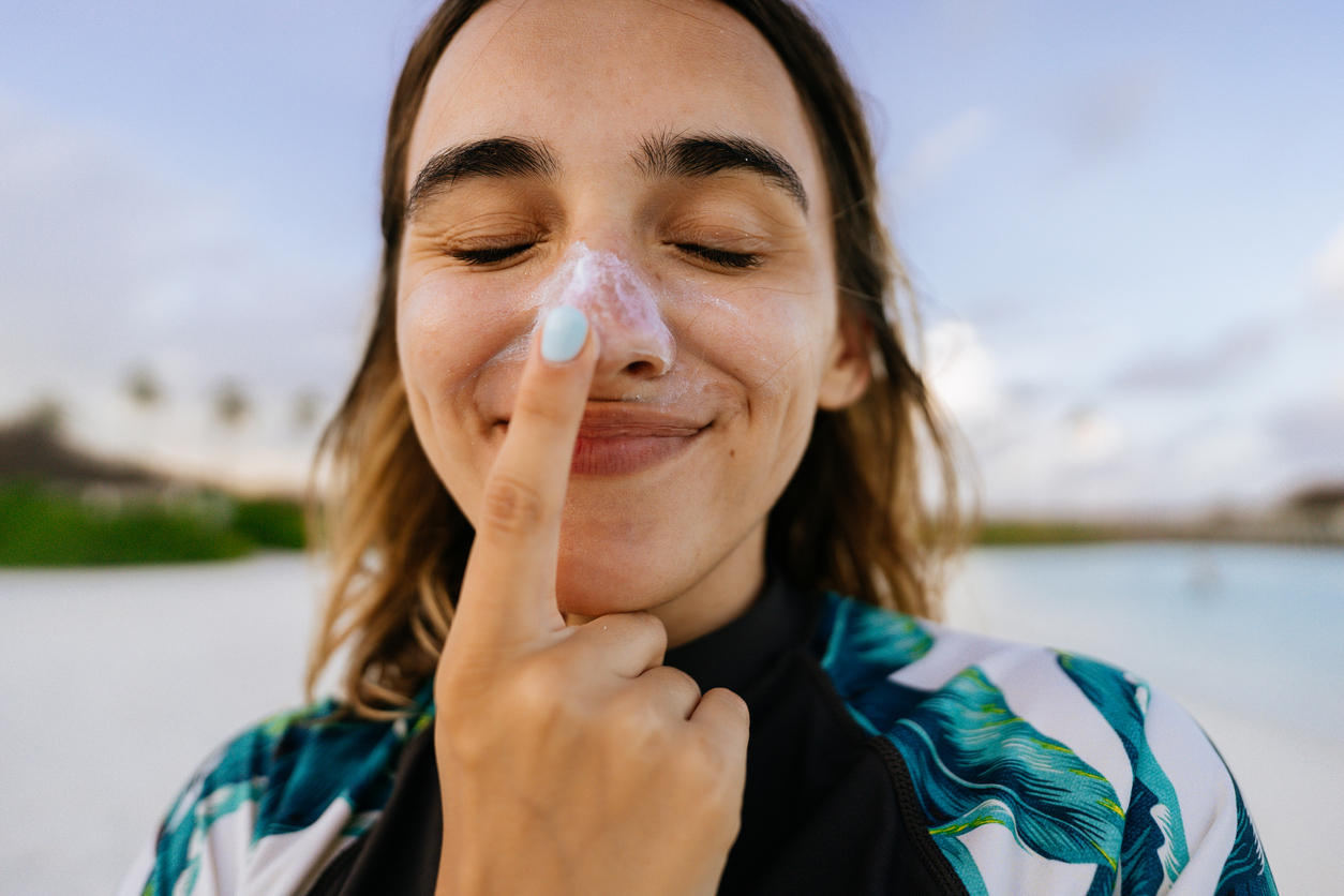 Femme mettant de la crème solaire sur son nez