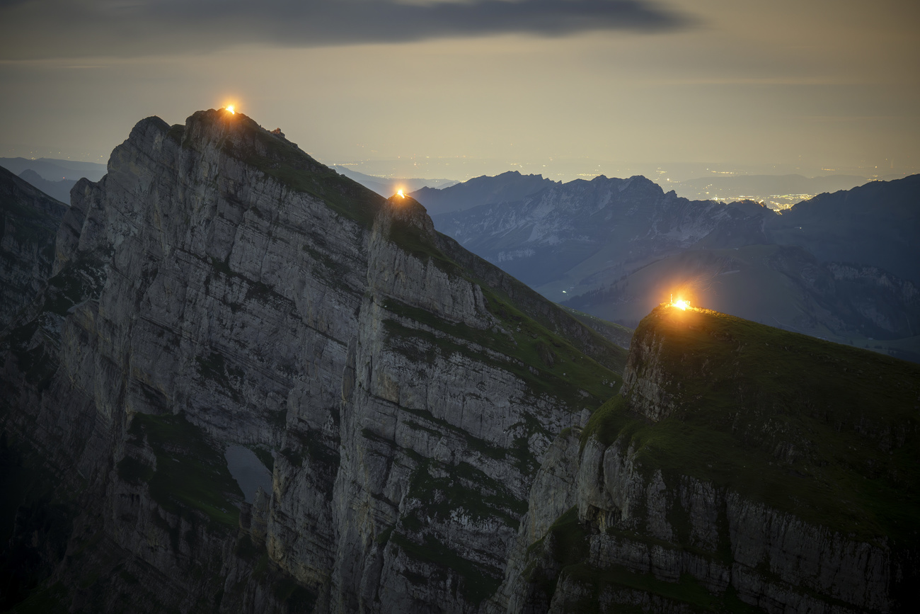 mountain ridge seen from a distance, with three bonfires on it