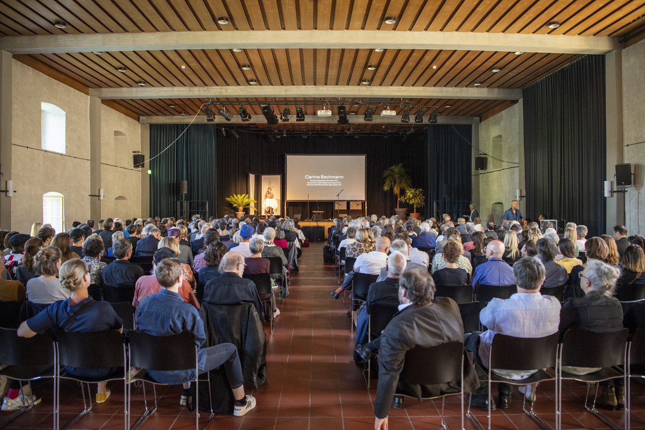 Menschen bicken in einem Saal in Solothurn auf Podium und Leinwand