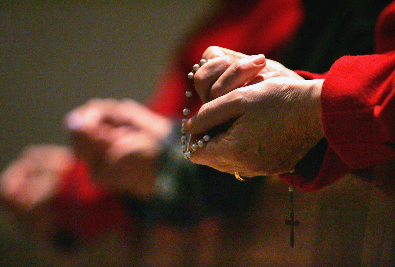 Manos sosteniendo un rosario con una cruz