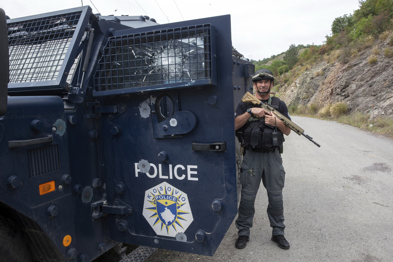 كوسوفو، بانجسكا: ضابط شرطة يقف بجوار مركبة مسلحة بها ثقوب الرصاص