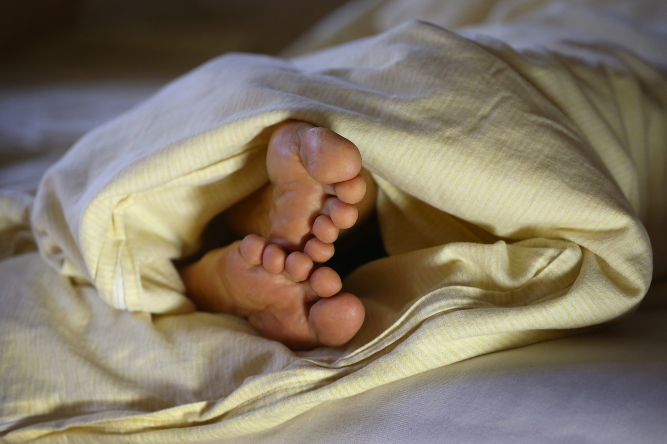 sleeping person with feet sticking out from under duvet